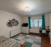 Na predaj rodinný dom v Trnovci nad Váhom - Izba v rodinnom dome s písacím stolom, posteľou, fotkami na stene a podlahou s dreveným dekorom.