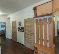 Na predaj rodinný dom v Trnovci nad Váhom - Chodba v rodinnom dome s podlahou s dreveným dekorom, vešiakmi a knihovničkou.