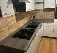 2-izb. byt, Nejedlého, Dúbravka, izby samostatné - Kuchyňa v 2-izbovom byte s plynovým sporákom, moderným obkladom a podlahou s dreveným dekorom.