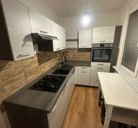2-izb. byt, Nejedlého, Dúbravka, izby samostatné - Kuchyňa v 2-izbovom byte s podlahou s dreveným dekorom a stenami z tehál.