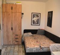 Útulný 3-izbový byt v Trnave na skok do Kamenáča! - Izba v 3-izbovom byte s posteľou, skriňou a podlahou s dreveným dekorom.