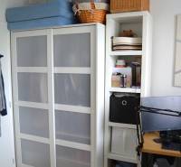 Útulný 3-izbový byt v Trnave na skok do Kamenáča! - Interiér 3-izbového bytu s bielou skriňou a poličkami, podlaha s dreveným dekorom.