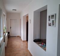 Dom na predaj Nová Ves nad Žitavou, pozemok 732 m2 - Chodba rodinného domu s dlažbou a bielymi stenami, s otvorenými dverami na pravej strane.