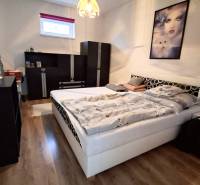 Dom na predaj Nová Ves nad Žitavou, pozemok 732 m2 - Spálňa v rodinnom dome s podlahou s dreveným dekorom, posteľou a čiernym nábytkom.