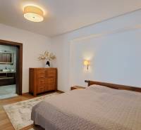 Lukratívny a priestranný 2-izbový apartmán v Mlynici na prenájom - Spálňa v 2-izbovom byte s posteľou, dreveným nábytkom a podlahou s dreveným dekorom.