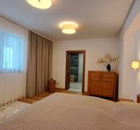 Lukratívny a priestranný 2-izbový apartmán v Mlynici na prenájom - Spálňa v 2-izbovom byte s dreveným dekorom, závesmi a svetlým nábytkom.