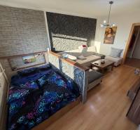 3 izbový byt 83 m² 2x balkón  Žiar nad Hronom centrum na predaj  - Obývacia izba s pohovkou, posteľou a podlahou s dreveným dekorom v 3-izbovom byte.