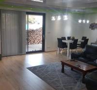 Predaj 4-izbového rodinného domu s veľkou záhradou v Semerove - Obývačka v rodinnom dome s podlahou s dreveným dekorom, pohovkou a jedálenským stolom.