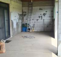 Predaj 4-izbového rodinného domu s veľkou záhradou v Semerove - Interiér rodinného domu s nevkusnými stenami, rebríkom a stavebným materiálom.