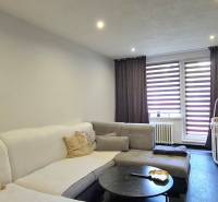 SLOVREAL - na predaj 2i byt Levice, 64m2 - Obývacia izba v 2-izbovom byte s pohovkou, konferenčným stolíkom a detskou postieľkou.