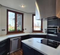 Reprezentatívny 5-izbový rodinný dom pri Piešťanoch - Kuchyňa v rodinnom dome s bielou doskou, čiernymi skrinkami a spotrebičmi.