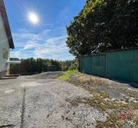 Veľký rodinný dom Podhradie  - Rodinný dom v Podhradí na Hlavnej ulici s garážou, stromom a betónovým povrchom.