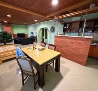 Veľký rodinný dom Podhradie  - Obývačka rodinného domu s tehlovým pultom, jedálňou, pohovkou a podlahou s dreveným dekorom.