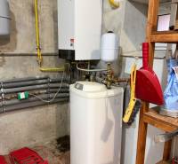 Veľký rodinný dom Podhradie  - Kúrenie a zásobník vody v pivnici rodinného domu s vybavením na poličke.