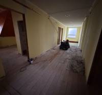 Veľký rodinný dom Podhradie  - Chodba v rodinnom dome s podlahou s dreveným dekorom, pripravená na renováciu.