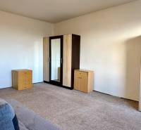 REZERVOVANÉ Na predaj 1 izbový byt, Bratislava, Dúbravka, Drobného - Izba v 1-izbovom byte s komodou, skriňou a kobercom na podlahe.