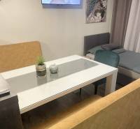 KRÁSNY DVOJPODLAŽNÝ RODINNÝ DOM NA PRENÁJOM - Obývacia časť s TV v rodinnom dome, sklenený stôl, pohovky, obraz páv, podlaha s dreveným dekorom.