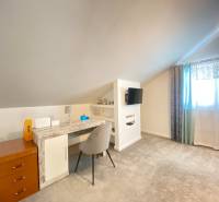 KRÁSNY DVOJPODLAŽNÝ RODINNÝ DOM NA PRENÁJOM - Izba v rodinnom dome s pracovným stolom, televízorom a svetlým kobercom.