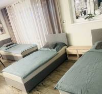 KRÁSNY DVOJPODLAŽNÝ RODINNÝ DOM NA PRENÁJOM - Tri postele, dve nočné stolíky a podlaha s dreveným dekorom v rodinnom dome.