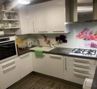 KRÁSNY DVOJPODLAŽNÝ RODINNÝ DOM NA PRENÁJOM - Kuchyňa v Rodinnom dome s bielymi skrinkami, dekoratívnym obkladom a podlahou s dreveným dekorom.