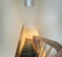 KRÁSNY DVOJPODLAŽNÝ RODINNÝ DOM NA PRENÁJOM - Schodisko s kobercom vedie nahor, nad ním visí svietidlo v rodinnom dome.