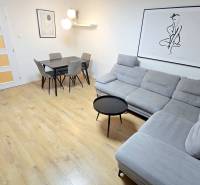 Moderný, rekonštruovaný 3i byt, pivnica, Jašíkova ul., Ružinov - Pošeň - Obývačka 3-izbového bytu so šedou sedačkou, jedálenským stolom a podlahou s dreveným dekorom.
