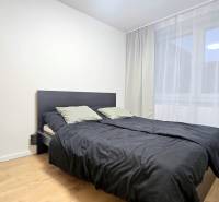 Moderný, rekonštruovaný 3i byt, pivnica, Jašíkova ul., Ružinov - Pošeň - Spálňa v 3-izbovom byte s posteľou, bielymi závesmi, a podlahou s dreveným dekorom.