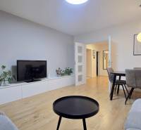 Moderný, rekonštruovaný 3i byt, pivnica, Jašíkova ul., Ružinov - Pošeň - Obývačka v 3-izbovom byte s podlahou s dreveným dekorom, TV skrinkou a jedálenským stolom.