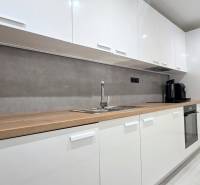 Moderný, rekonštruovaný 3i byt, pivnica, Jašíkova ul., Ružinov - Pošeň - Kuchynská linka v 3-izbovom byte s bielymi skrinkami a dreveným dekorom.