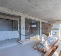 NA PREDAJ polyfunkčná budova v centre obce Veľké Leváre - Interiér budovy vo výstavbe s nerovnou tehlovou stenou a stavebným materiálom na podlahe.