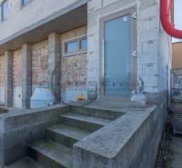 NA PREDAJ polyfunkčná budova v centre obce Veľké Leváre - Budova vo Veľkých Levároch s nedokončenou fasádou a schodmi na betónovom základe.