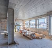 NA PREDAJ polyfunkčná budova v centre obce Veľké Leváre - Interiér budovy s tehlovými stenami, veľkými oknami a stavebným materiálom.