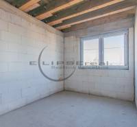 NA PREDAJ polyfunkčná budova v centre obce Veľké Leváre - Prázdna miestnosť s bielymi stenami, dreveným stropom a veľkým oknom v budove.