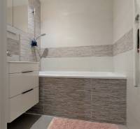 ŠTÝLOVÝ 3,5-IZBOVÝ BYT S NÁBYTKOM NA MIERU, A. HLINKU, ZVOLEN - Kúpeľňa s vaňou, sivými obkladmi a ružovým kobercom v 3-izbovom byte.