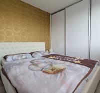 ŠTÝLOVÝ 3,5-IZBOVÝ BYT S NÁBYTKOM NA MIERU, A. HLINKU, ZVOLEN - Spálňa v 3-izbovom byte s tapetou a vstavanou skriňou, podlaha s dreveným dekorom.