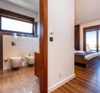 Novalja – luxusná vila s bazénom, jacuzzi a výhľadom na more - Interiér vily s podlahou s dreveným dekorom, spálňa a kúpeľňa s veľkým oknom.