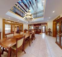 Veľkometrážny dom s wellness, bazénom a investičným potenciálom - Jedáleň v rodinnom dome s veľkým dreveným stolom, lustrom a vitrínami s porcelánom.