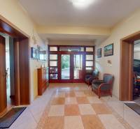 Veľkometrážny dom s wellness, bazénom a investičným potenciálom - Chodba v rodinnom dome s dlažbou a dreveným nábytkom, vedúca do garáže.