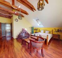 Veľkometrážny dom s wellness, bazénom a investičným potenciálom - Podkrovná izba s drevenými trámami, veľkou posteľou a podlahou s dreveným dekorom v rodinnom dome.