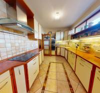 Veľkometrážny dom s wellness, bazénom a investičným potenciálom - Kuchyňa v rodinnom dome s drevenými skrinkami a dlažbou na podlahe.