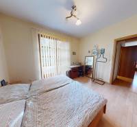 Veľkometrážny dom s wellness, bazénom a investičným potenciálom - Spálňa s dvojposteľou a stolíkom, podlaha s dreveným dekorom v rodinnom dome.