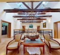 Veľkometrážny dom s wellness, bazénom a investičným potenciálom - Podkrovný priestor v rodinnom dome s dekoratívnou loďou, sedacím kútom a podlahou s dreveným dekorom.