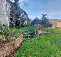 NA PREDAJ rodinný dom - Lehota nad Rimavicou - Dvor s rodinným domom, trávnik, stromy a schodisko v prírodnom prostredí.