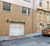 Na predaj parkovacie miesto, Beskydská, Bratislava, Staré Mesto - Brána v centre mesta s dopravnými značkami a hnedým autom, garáže v pozadí.