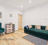 NA PREDAJ 4-IZBOVÝ RODINNÝ DOM V KOLÁROVE - Obývacia izba s podlahou s dreveným dekorom, zeleným kreslom a pohovkou v rodinnom dome.