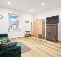 NA PREDAJ 4-IZBOVÝ RODINNÝ DOM V KOLÁROVE - Obývačka v rodinnom dome s pohovkou, televízorom a podlahou s dreveným dekorom.