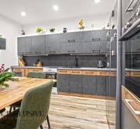 NA PREDAJ 4-IZBOVÝ RODINNÝ DOM V KOLÁROVE - Kuchyňa rodinného domu s podlahou s dreveným dekorom a šedým nábytkom.