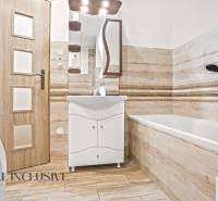 NA PREDAJ 4-IZBOVÝ RODINNÝ DOM V KOLÁROVE - Kúpeľňa v rodinnom dome s vaňou, podlahou s dreveným dekorom a práčkou.