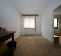 3-izb. byt v rekonštrukcii, Ľubochňa okres Ružomberok - Izba v 3-izbovom byte s podlahou s dreveným dekorom, viditeľné dva okná a radiátor.