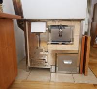 3-izb. byt v rekonštrukcii, Ľubochňa okres Ružomberok - Kachľová pec v 3-izbovom byte s podlahou s dreveným dekorom a dreveným nábytkom.